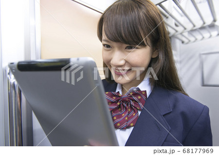 電車でタブレットPCを見る女子高校生 電車でタブレットPCを見る女子高校生 68177969