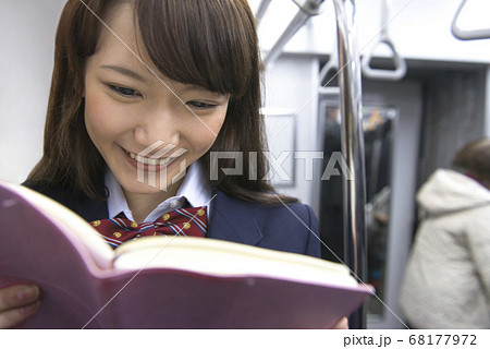電車で本を読む女子高校生 68177972