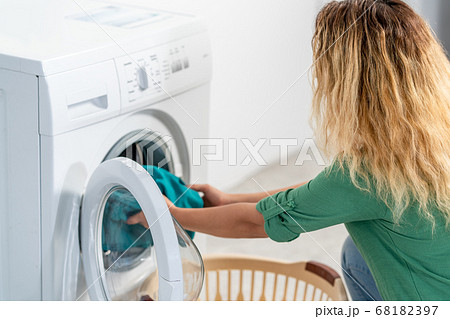 Young woman, load the wash machine for cleaning laundrys Young woman, load the wash machine for cleaning laundrys 68182397