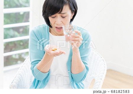 クスリを飲もうとしているミドル女性 68182583