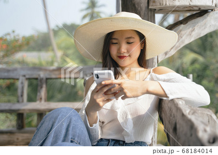 Happy asian girl playing with smartphone. 68184014