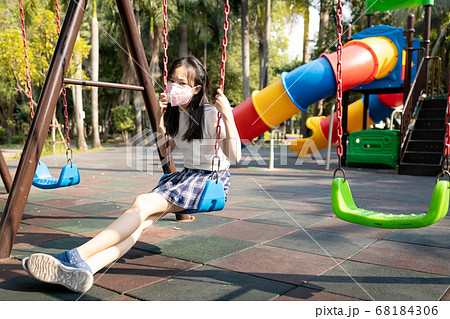 Asian child girl wearing protective mask in playground,girl prevent infection from Covid-19,dangerous situation,severe Coronavirus outbreak,risks,spread of Covid-19 virus is a serious global problem 68184306