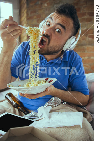 Lazy man living the whole life in his bed surrounded with messy 68184773