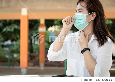 Sick asian female people with cold,flu,woman wearing hygienic mask and touch the neck with fever,cough,sore throat or Corona virus Covid-19 symptoms,feel unwell, ill,medical treatment,healthcare 68185033