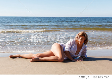young woman in a white shirt lies on the sand of young woman in a white shirt lies on the sand of 68185792
