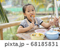 Asian girl eating deep fried shrimp with fork. 68185831