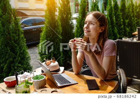 young woman using laptop in a cafe on a summer terrace 68186242