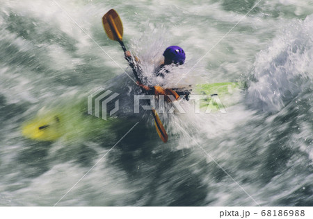 Whitewater kayaker paddles and surds large river rapids on a fast flowing river Whitewater kayaker paddles and surds large river rapids on a fast flowing river 68186988