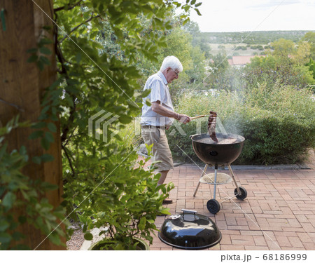 senior man grilling ribs on front porch senior man grilling ribs on front porch 68186999