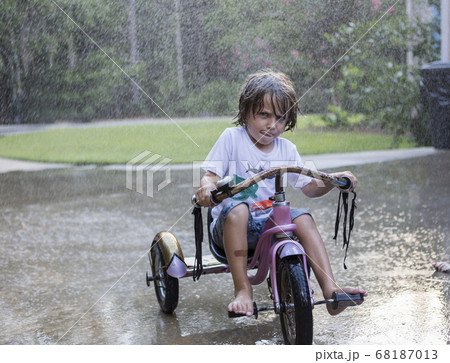 5 year old boy riding his tricycle bike in the rain 5 year old boy riding his tricycle bike in the rain 68187013