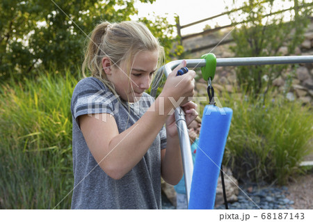 11 year old girl fixing child's swing in backyard 68187143