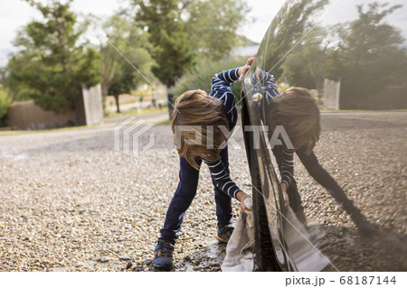 4 year old boy washing a car in the parking lot 68187144