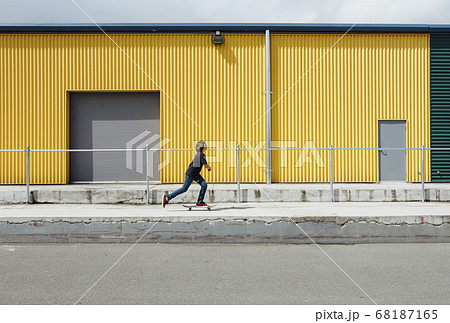 Teenage boy skateboarding in front of industrial warehouse loading zone Teenage boy skateboarding in front of industrial warehouse loading zone 68187165