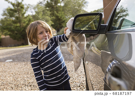 Four year old boy polishing a car exterior with cleaner and a cloth Four year old boy polishing a car exterior with cleaner and a cloth 68187197