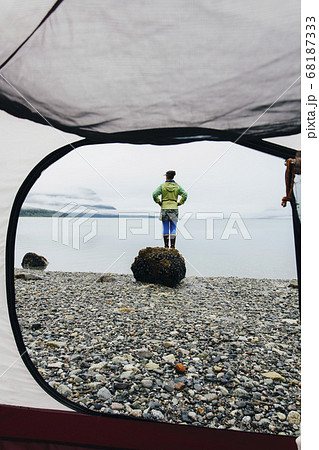 View through camping tent doorway of woman standing on beach,an inlet on the Alaska coastline. View through camping tent doorway of woman standing on beach,an inlet on the Alaska coastline. 68187333