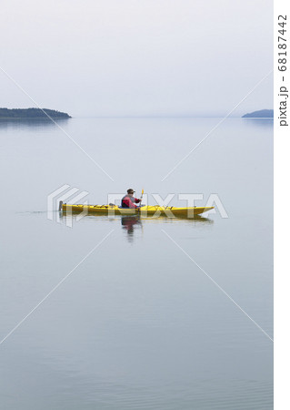 Female sea kayaker paddling pristine waters of Muir Inlet, overcast sky in distance, Glacier Bay National Park, Alaska 68187442