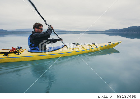 Man sea kayaking inan inlet on the Alaska coastline. Man sea kayaking inan inlet on the Alaska coastline. 68187499