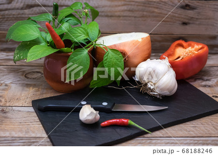 cooking ingredients and spices such as chili, garlic, onion and pepper on a blackboard to cut and prepare them for cooking cooking ingredients and spices such as chili, garlic, onion and pepper on a blackboard to cut and prepare them for cooking 68188246