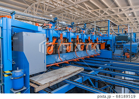 Wooden boards moving on conveyor. Cutting log on industrial saw workbench at modern sawmill factory. Lumber industry. Woodworking factory. Legal sawmill. 68189519