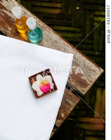 Bath towel, bath gel and candle flower shape as spa set on wooden floor in the garden Bath towel, bath gel and candle flower shape as spa set on wooden floor in the garden 68190057