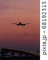 夕焼けの時間帯に着陸する飛行機 68192315