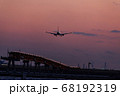 夕焼けの時間帯に着陸する飛行機 68192319