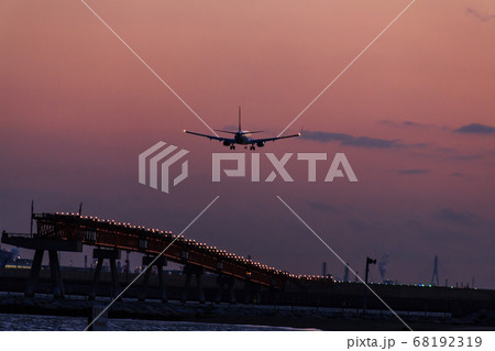 夕焼けの時間帯に着陸する飛行機 68192319