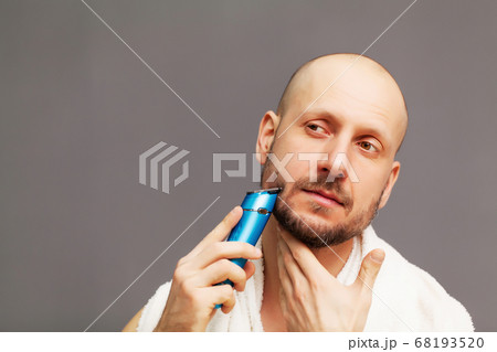 Handsome young bearded man trimming his beard with trimmer 68193520