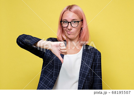 Young businesswoman in suit and glasses showingthumb down 68195507
