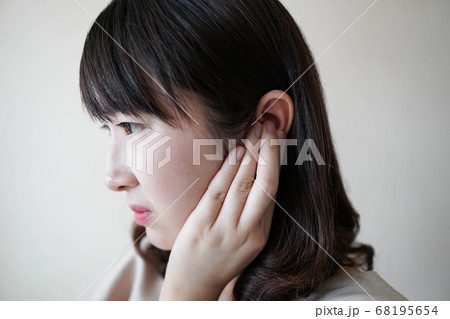 Young asian woman suffering from ear pain and tinnitus. Cause of earache includes otitis, earwax buildup, a foreign object in the ear, sinus infection or changes in air pressure. Ear disease concept. Young asian woman suffering from ear pain and tinnitus. Cause of earache includes otitis, earwax buildup, a foreign object in the ear, sinus infection or changes in air pressure. Ear disease concept. 68195654