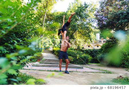 Beautiful man and woman doing acroyoga in the garden or park 68196457