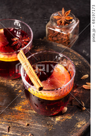 Mulled wine with slice of orange and spices on a wooden cutting board Mulled wine with slice of orange and spices on a wooden cutting board 68197173