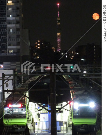 空蝉橋から眺める山手線大塚駅と満月とスカイツリーの写真素材