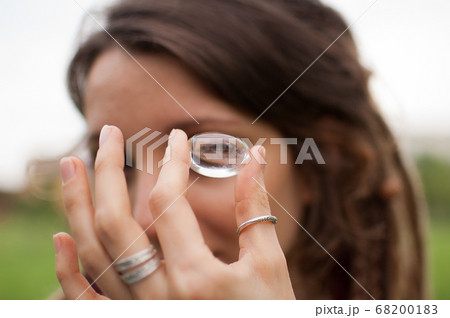 Young beautiful girl with dreadlocks holds in hand rhinestone, transparent quartz, natural stone outdoors during morning near her face Young beautiful girl with dreadlocks holds in hand rhinestone, transparent quartz, natural stone outdoors during morning near her face 68200183