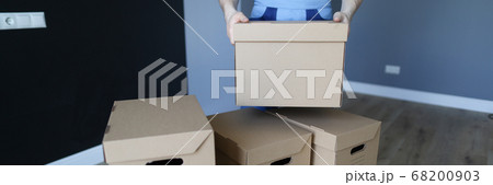 Loader stacks cardboard boxes in an empty room Loader stacks cardboard boxes in an empty room 68200903