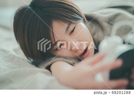 めざまし時計を止める30代女性 68201288