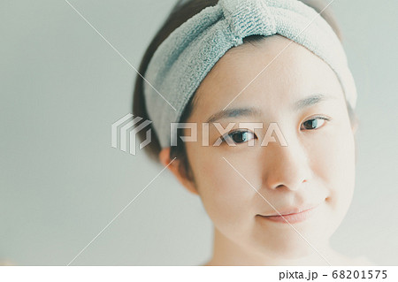 ヘアバンドをして洗顔をする30代女性の写真素材