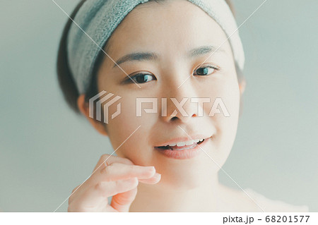 フェイスケアをするヘアバンドをした30代女性の写真素材