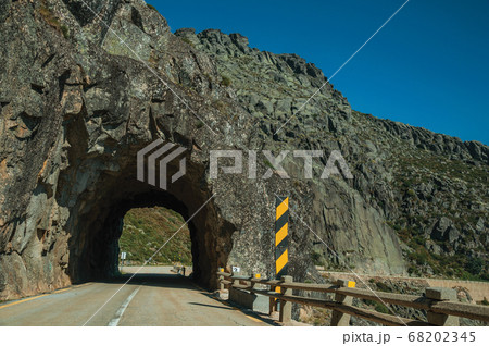 Road on rocky landscape passing through tunnel 68202345