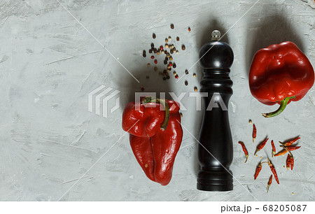 Two shriveled red peppers, spices and a pepper mill on a grey rough surface, top view with space Two shriveled red peppers, spices and a pepper mill on a grey rough surface, top view with space 68205087