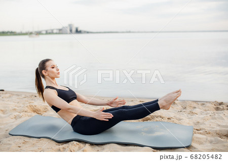 fitness model goes in for sports on the beach. Does abdominal exercises 68205482