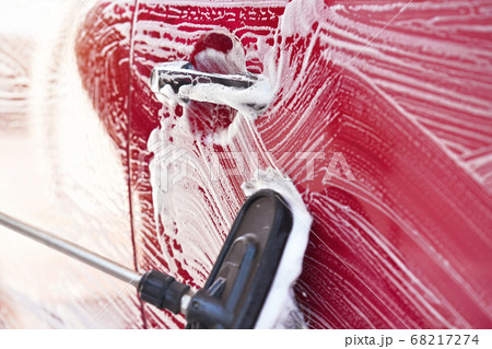 Red car washed in self serve carwash , detail on brush leaving strokes on side door, wide banner with empty space for text left side 68217274