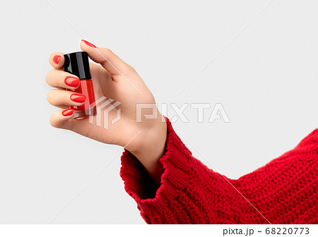 Woman's hand with red manicure holding a bottle of nail polish 68220773