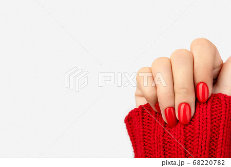 Woman's hand in sweater with red manicure on gray background Woman's hand in sweater with red manicure on gray background 68220782