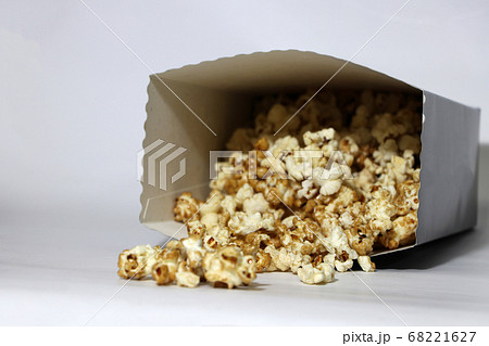Heap of chocolate and caramel popcorn from paper box on the white floor. 68221627