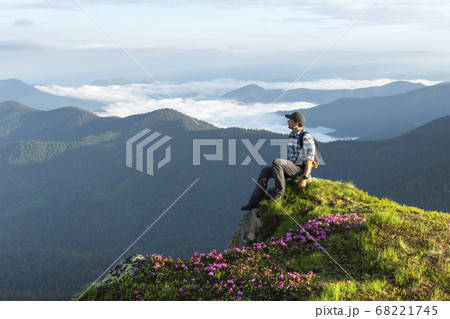 A tourist sits on the edge of a cliff A tourist sits on the edge of a cliff 68221745