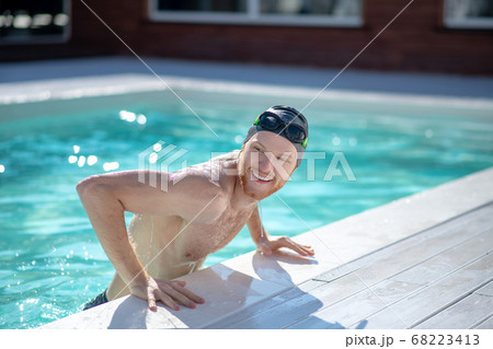 Smiling man in pool looking sideways interested Smiling man in pool looking sideways interested 68223413
