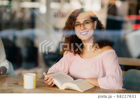 Young woman with eyeglasses reading book in cafe Young woman with eyeglasses reading book in cafe 68227631