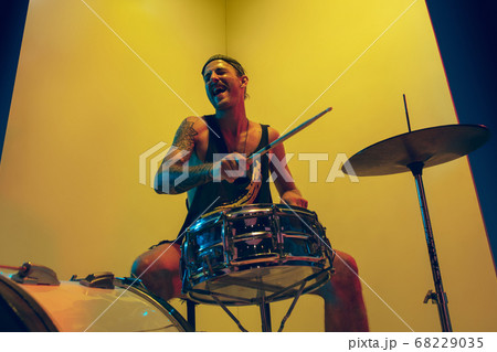 Young caucasian musician inspired performing on yellow background in neon light Young caucasian musician inspired performing on yellow background in neon light 68229035