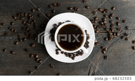 Coffee cup with roasted coffee beans on wooden table background. Mug of black coffe with scattered coffee beans on a wooden table. Fresh coffee beans. Coffee cup with roasted coffee beans on wooden table background. Mug of black coffe with scattered coffee beans on a wooden table. Fresh coffee beans. 68232503